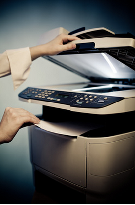 Hands pulling paper out of a printer