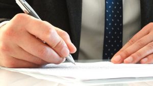 man in suit signing a document