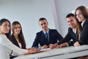 five people sitting around a confrence table smiling